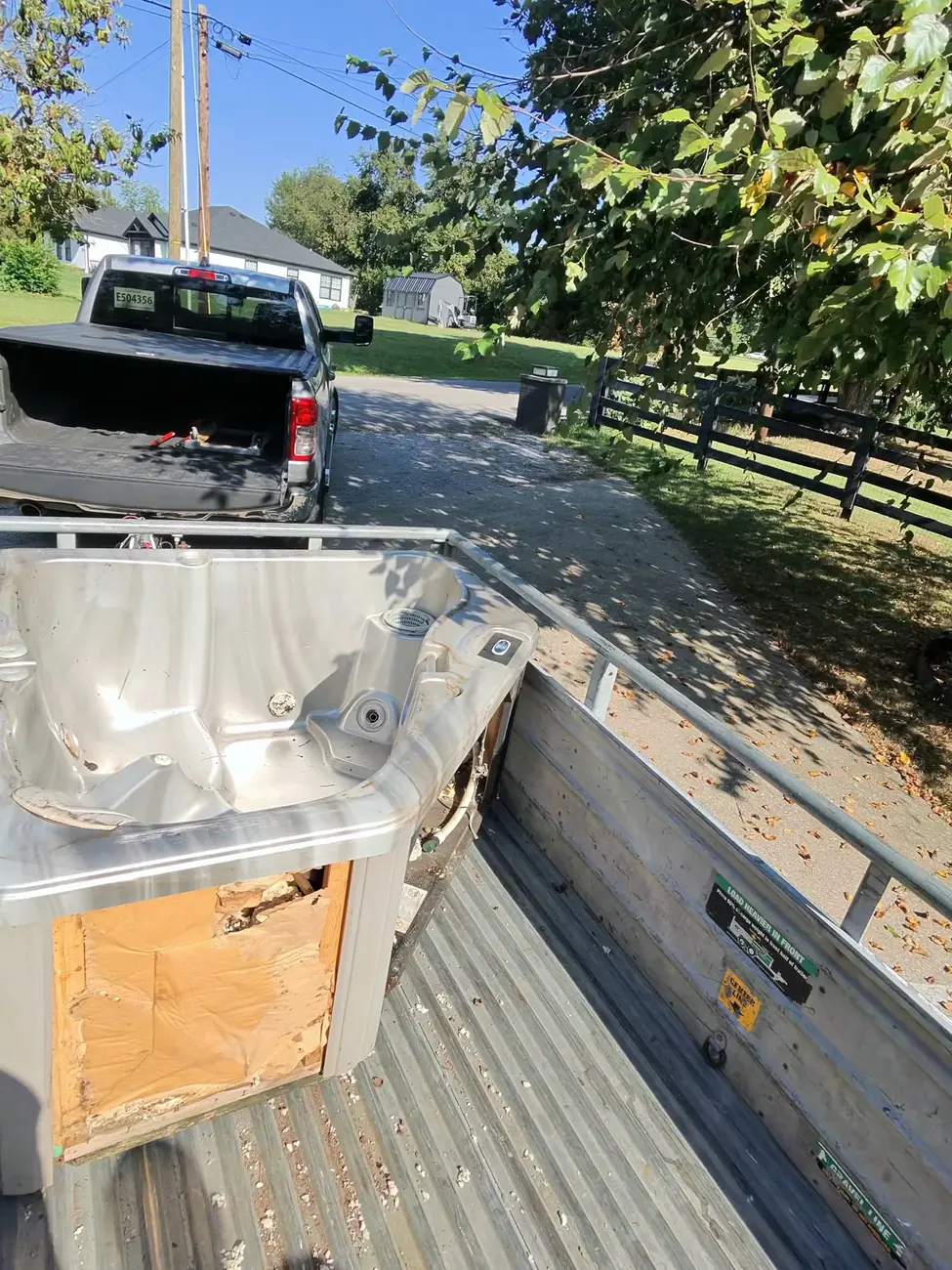 The removed hot tub shell strapped on the trailer in the driveway, ready to haul.