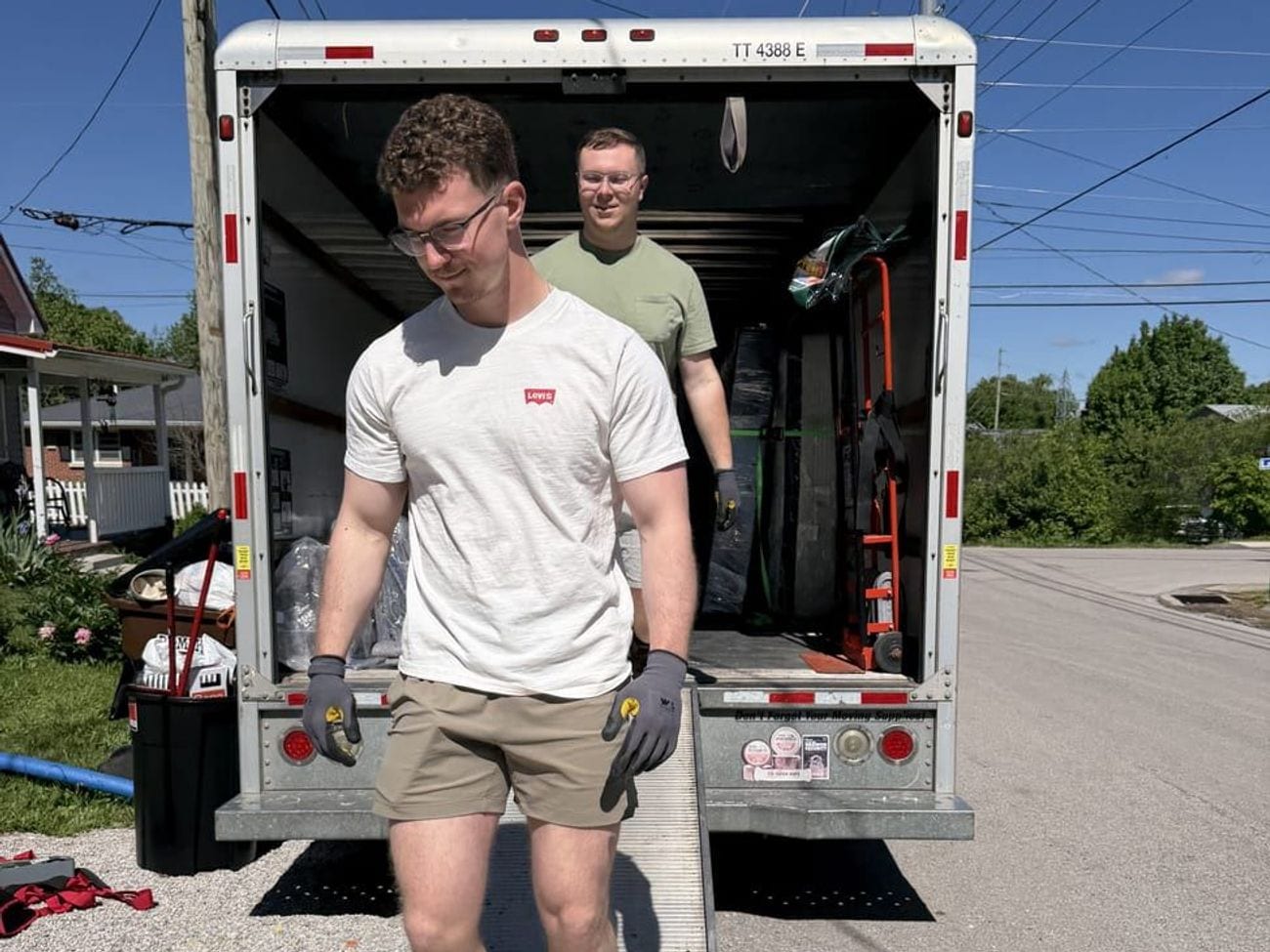 Two New Creation Cleanup crew members walking down the box truck ramp during a cleanout.