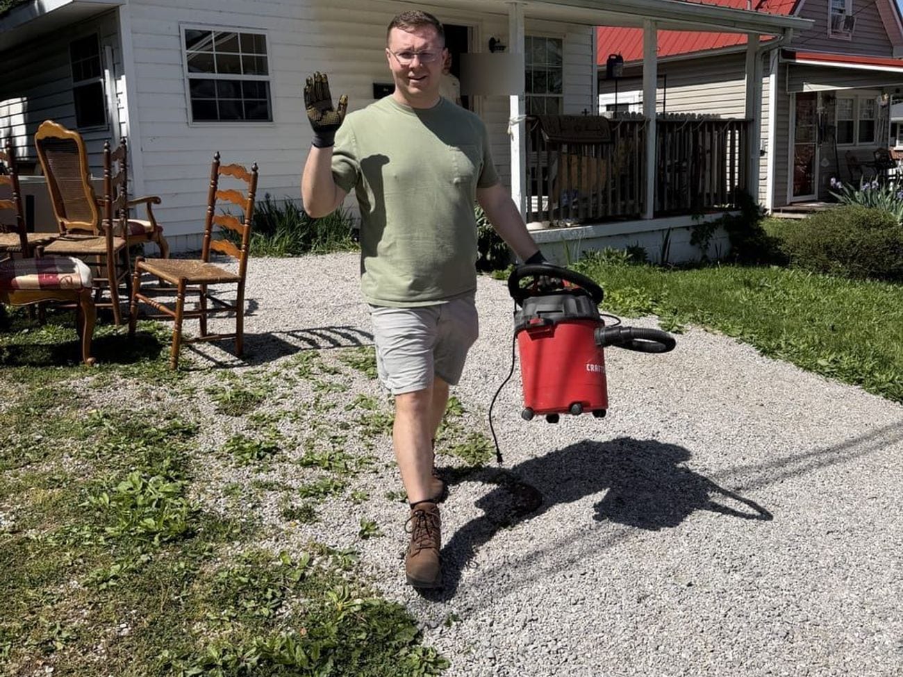 A crew member carrying a shop vacuum out after cleaning up the work area.